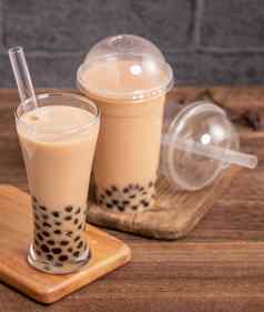 美味的泡沫牛奶茶稻草喝玻璃木表格背景概念减少塑料台湾关闭复制空间