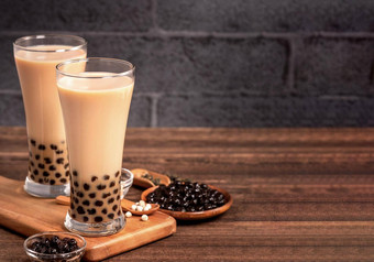 美味的泡沫牛奶茶木薯珍珠球玻璃木表格黑暗灰色的砖背景受欢迎的食物喝台湾关闭