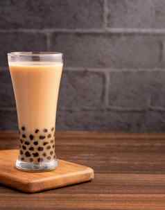 美味的泡沫牛奶茶木薯珍珠球玻璃木表格黑暗灰色的砖背景受欢迎的食物喝台湾关闭