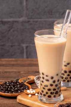 美味的泡沫牛奶茶稻草喝玻璃木表格背景概念减少塑料台湾关闭复制空间
