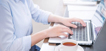业务概念女人蓝色的衬衫打字电脑咖啡办公室表格背光太阳眩光效果关闭一边视图复制空间