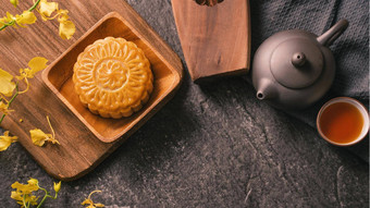 <strong>中秋</strong>节日传统的食物概念美丽的月亮蛋糕黑色的板岩表格茶糕点模具花前视图平躺复制空间