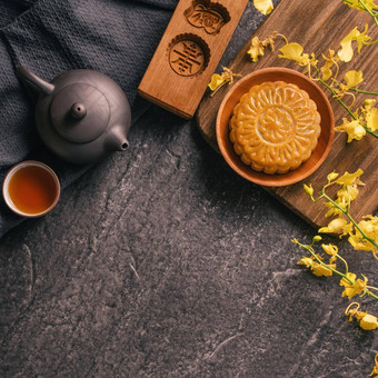 <strong>中秋节</strong>日传统的食物概念美丽的月亮蛋糕黑色的板岩表格茶糕点模具花前视图平躺复制空间