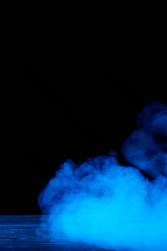 概念上的图像蓝色的烟孤立的黑暗黑色的背景木表格