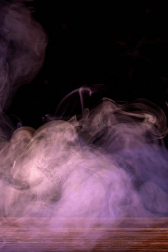 概念上的图像多色的烟孤立的黑暗黑色的背景木表格