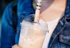 年轻的女孩牛仔布夹克喝棕色（的）糖味木薯珍珠泡沫牛奶茶玻璃稻草晚上市场台湾关闭散景