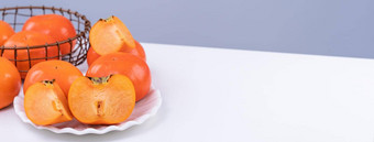 新鲜的美丽的切片甜蜜的柿子脚孤立的白色厨房表格灰色的蓝色的背景中国人月球一年设计概念关闭