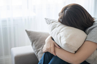 女人坐着沙发上拥抱枕头孤独悲伤概念
