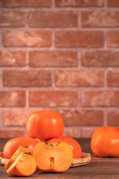 切片甜蜜的柿子脚竹子筛篮子黑暗木表格红色的砖墙背景中国人月球一年水果设计概念关闭