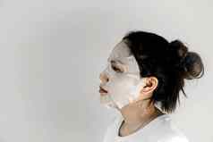一边视图亚洲女人穿白色t恤覆盖脸表面具