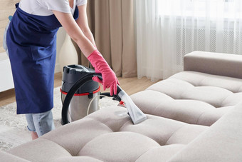 女人清洁沙发上真空更清洁的首页清洁服务概念