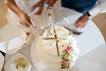 新娘新郎切割时尚的婚礼蛋糕婚礼宴会新婚夫妇持有刀切割婚礼蛋糕