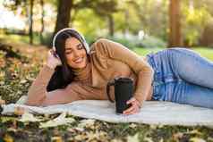 女人听音乐喝咖啡享受秋天休息公园