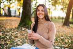 女人发短信消息坐着公园享受秋天