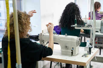 年轻的裁缝缝衣服缝纫机讲习班工作室