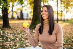 女人吃苹果享受秋天休息公园