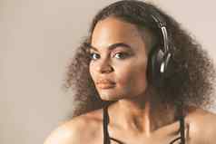 年轻的非裔美国人女孩听音乐耳机穿黑色的前孤立的灰色背景在情感上移动概念情绪面部表达式健美的图像