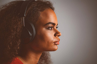 捕捉氛围音乐年轻的非裔美国人女孩横盘整理听音乐穿耳机孤立的灰色背景在情感上移动有趣的关闭