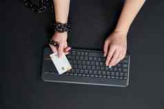女人金属链持有信贷卡键盘在线购物上瘾概念