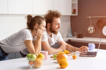 靠厨房表格夫妇看浪漫的电影流媒体社会媒体视频美丽的年轻的夫妇会说话的视频调用移动PC年轻的夫妇厨房首页