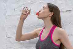 年轻的运动员女人需要打破喝水塑料瓶年轻的女人喝水工作健身房健康体育运动概念