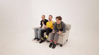 快乐赢得游戏的家伙黄色的衬衫玩视频游戏朋友坐着白色沙发孤立的白色背景的家伙反应赢得失去游戏概念镜头