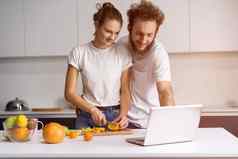 男人。靠女孩微笑看浪漫的电影美丽的年轻的夫妇会说话的视频调用移动PC年轻的夫妇烹饪健康的食物厨房首页