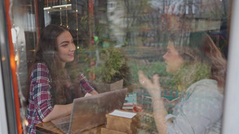 视图玻璃学生女孩会说话的享受咖啡咖啡商店客户走背景坐表格聊天工作移动PC镜头