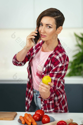 会说话的电话显示柠檬年轻的漂亮的女人鲍勃发型准备食物厨房健康的食物首页健康的食物离开素食主义者概念房子概念