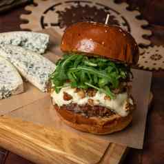 新鲜的工艺牛肉汉堡新鲜的芝麻菜沙拉新鲜的蓝色的奶酪片铺设餐厅概念街食物概念