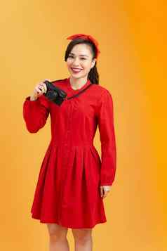 有吸引力的年轻的漂亮的亚洲女人红色的衣服持有相机橙色背景