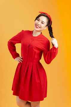 肖像快乐的年轻的亚洲女人红色的衣服摆姿势橙色背景