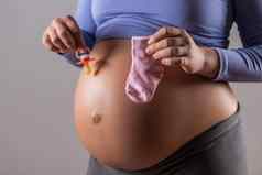 胃怀孕了女人持有奶嘴袜子婴儿女孩