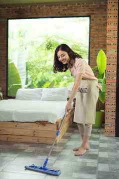 做家务管家概念女人清洁地板上拖把在室内