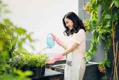 年轻的亚洲女园丁浇水植物