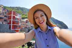微笑旅游女孩采取自拍照片阳光明媚的一天riomaggiore村五渔村意大利