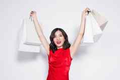 快乐的时尚亚洲女人穿红色的衣服购物袋站白色