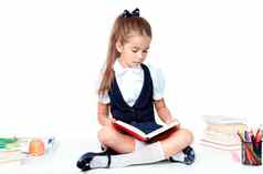 年轻的可爱的女孩坐着表格阅读书