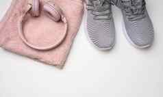 一对灰色的纺织运动鞋无线耳机纺织粉红色的毛巾白色背景集体育运行