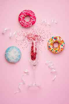 平躺庆祝活动香槟玻璃色彩斑斓的聚会，派对飘带美味的甜甜圈粉红色的背景