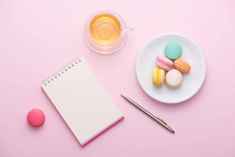 平铺笔记本<strong>蛋糕</strong>macaron杯茶花粉红色的表格美丽的早餐蛋白杏仁饼干