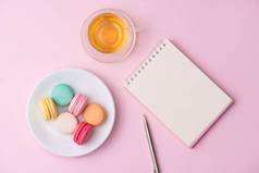 平铺笔记本蛋糕macaron杯茶粉红色的表格美丽的早餐蛋白杏仁饼干