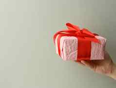 女手持有粉红色的礼物盒子灰色的背景快乐生日概念