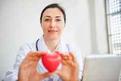 医疗心脏病专家医生持有红色的心给病人女医生医生显示心模型病人检查房间健康检查检查医学心脏病学概念