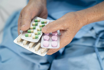 亚洲高级上了年纪的夫人女人病人持有抗生素胶囊药片泡包装治疗感染病人医院药店药店概念