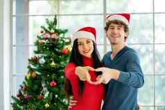夫妇年轻的男人。女人手使象征心保持房间装饰圣诞节节日幸福