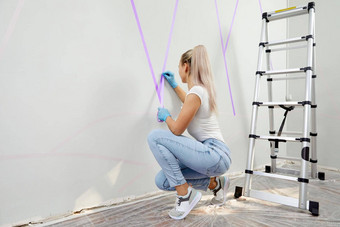 年轻的女人准备<strong>墙绘</strong>画站梯应用屏蔽磁带墙Diy项目