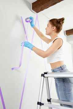 年轻的女人油漆刷绘画墙房子首页装饰概念