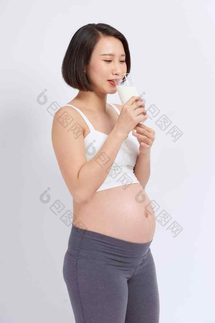 怀孕了女人持有玻璃牛奶手好Healty孤立的白色背景