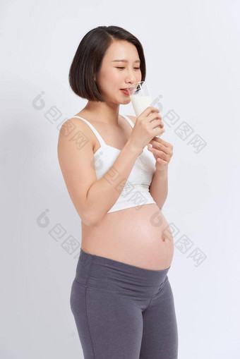 怀孕了女人持有玻璃牛奶手好Healty孤立的白色背景